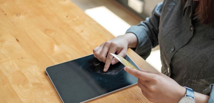 woman hand holding credit card with using laptop for online shopping while making orders at home. business, lifestyle, technology, ecommerce, digital banking and online payment concept..