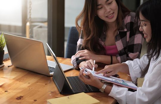 Two businesswomen discussing for financial chart report in office, discussing business together in a meeting.