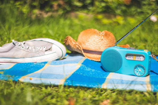 Picnic blanket with sneakers, straw hat, and radio