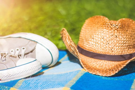 Picnic blanket with sneakers and straw hat