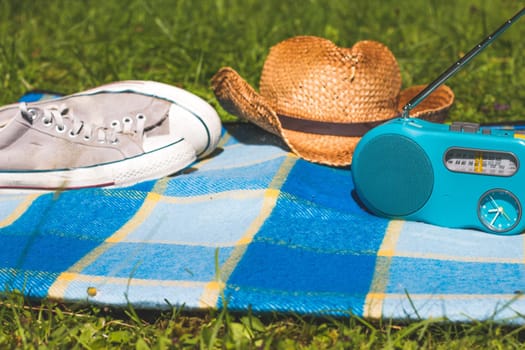 Picnic blanket with sneakers, straw hat, and radio