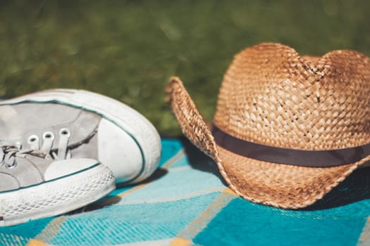 Picnic blanket with sneakers and straw hat