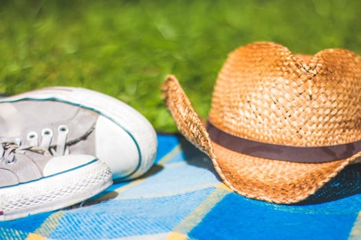 Picnic blanket with sneakers and straw hat