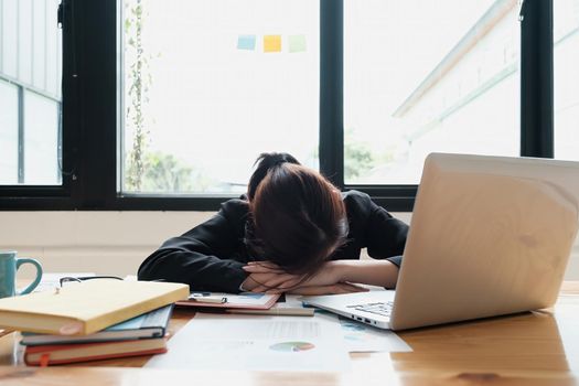 Stressed business woman hard working until morning and tired and sleep at table in office while project deadlines. finance, account, tax, audit concept