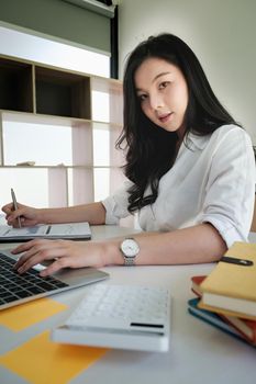 Business accounting using calculator applicatopn on laptop on wooden desk in office. Tax, Accounting, Statistics and Analytic research concept