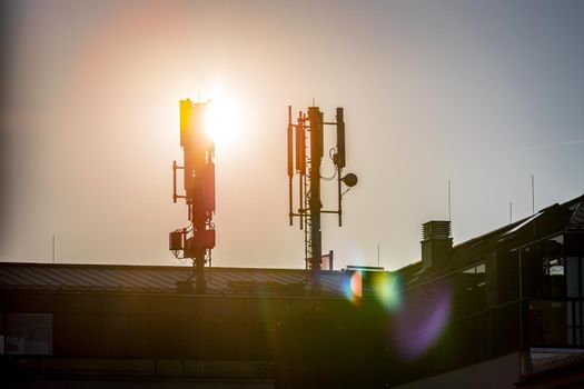 Silhouette of communication or cell tower on the rooftop of a building, evening sunshine