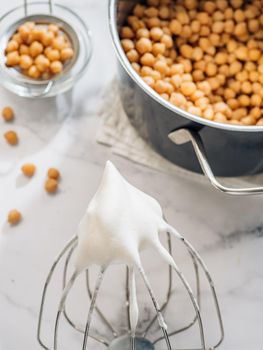 Whipped aquafaba on planetary mixer whisk, vertical. Chickpea water brine aquafaba whipped. Egg replacement in coocking. Vegan concept. Top view or flat lay