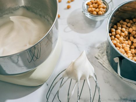 Whipped aquafaba in planetary mixer. Chickpea water brine aquafaba whipped. Egg replacement in coocking. Vegan concept. Top view or flat lay. Hard light