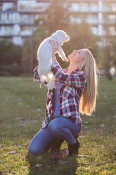 Beautiful woman spending time with her Maltese dog outdoor.