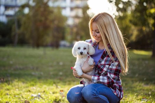 Beautiful woman spending time with her Maltese dog outdoor.