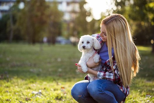 Beautiful woman spending time with her Maltese dog outdoor.