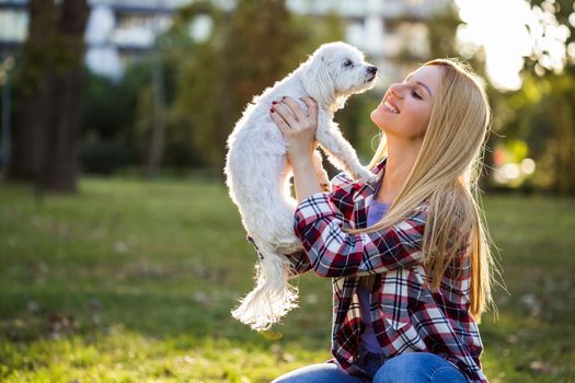 Beautiful woman spending time with her Maltese dog outdoor.