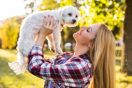 Beautiful woman spending time with her Maltese dog outdoor.