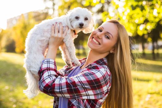 Beautiful woman spending time with her Maltese dog outdoor.