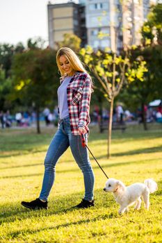 Beautiful woman walking with her Maltese dog in the park.