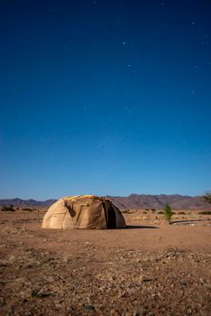 desert landscape with tradirional Nama tribe hut in Namibia by night