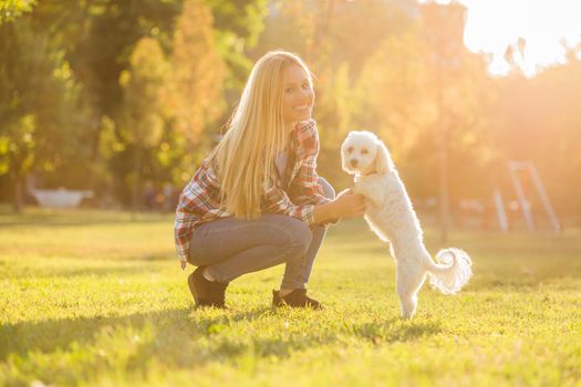 Beautiful woman spending time with her Maltese dog outdoor.