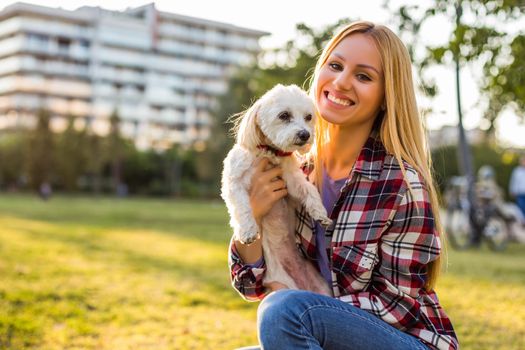 Beautiful woman spending time with her Maltese dog outdoor.