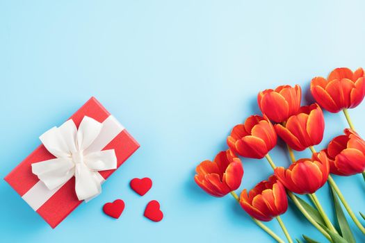 Mother's day background concept. Top view design of holiday greeting gift with red tulip bouquet on bright blue table background