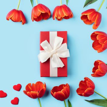 Mother's day background concept. Top view design of holiday greeting gift with red tulip bouquet on bright blue table background