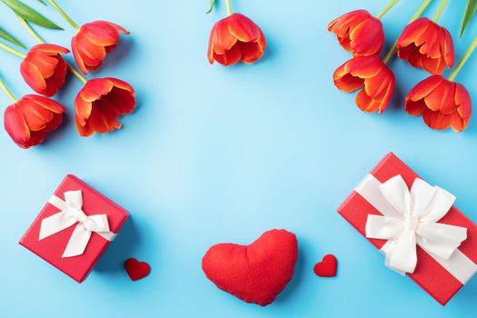 Mother's day background concept. Top view design of holiday greeting gift with red tulip bouquet on bright blue table background