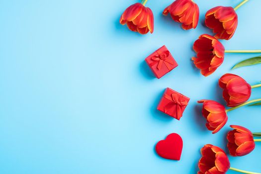 Mother's day background concept. Top view design of holiday greeting gift with red tulip bouquet on bright blue table background