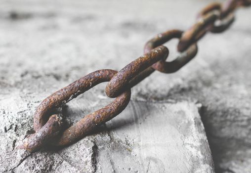 Rusty chain in the cement. Retro style photo. Shallow DOF.