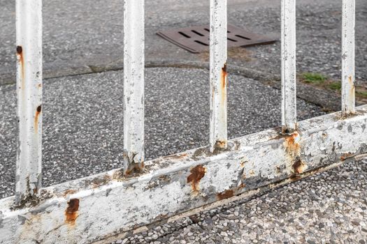 Rusty white gate on gray street background.