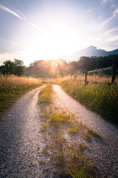 Scenic sunset view over country road, meadow, hills and mountains.