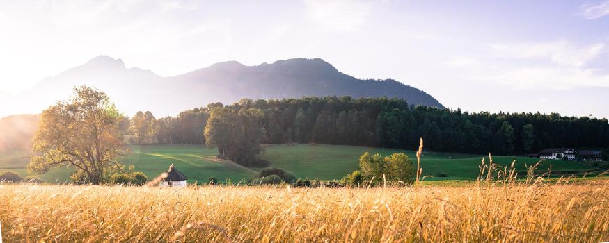 Scenic sunset view over meadow, hills and mountains.