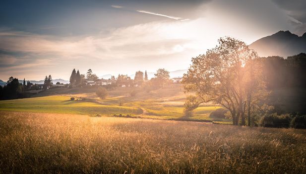 Scenic sunset view over meadow, hills and mountains.