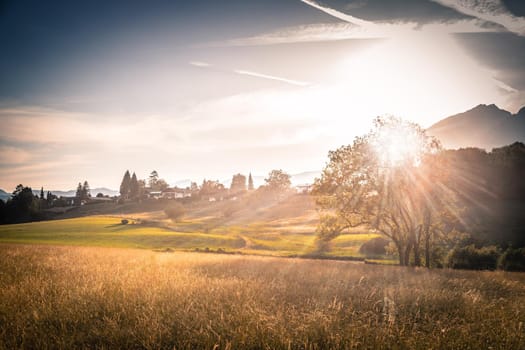Scenic sunset view over meadow, hills and mountains.