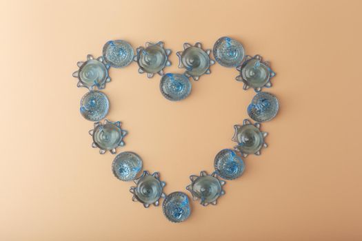 Heart made of blue glass sea shells on beige background. Concept of sea, ocean and summer vacations