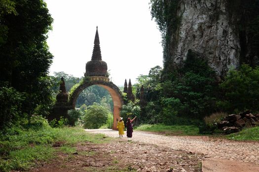 The scenery of the Khao Na Nai Luang Dharma Park or Phutthawadee arch with the orange flowers and green grass foreground at Surat Thani Province, Thailand. 