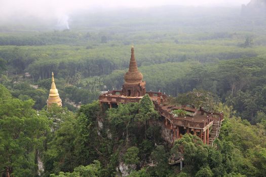 Landscape of beautiful sunrise with pagoda on peak mountain and tree with misty morning at Na Nai Luang temple , Surat Thani Province, Southern of Thailand