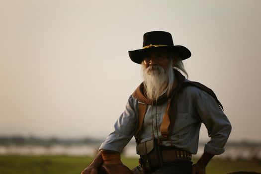 cowboy on horseback against a beautiful sunset, cowboy and horse at first light, mountain, river and lifestyle with natural light background.