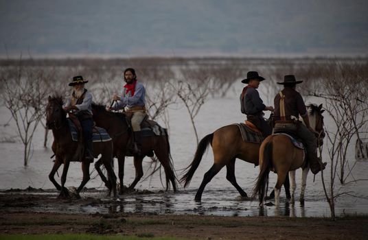 cowboy on horseback against a beautiful sunset, cowboy and horse at first light,mountain, river and lifestyle with natural light background