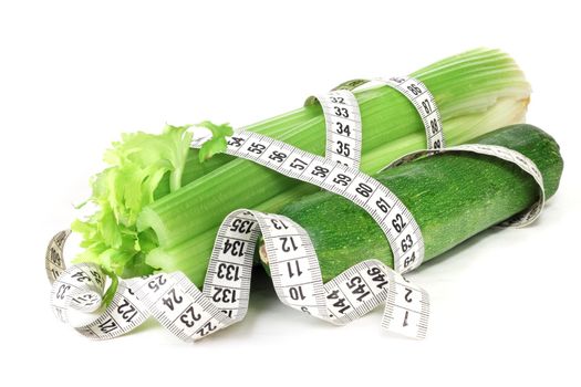 Celery zucchini and measure tape diet weight loss concept isolated on white background