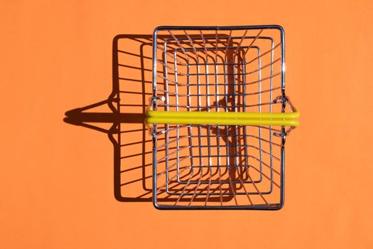 steel supermarket basket with hard shadow on colored background. High quality photo