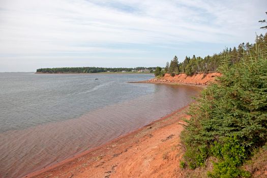 Red clay beach with sand on the ocean on a summer day in Prince Edward island