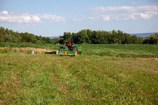 tractor in a large outdoor field on a sunny summer day on the farm