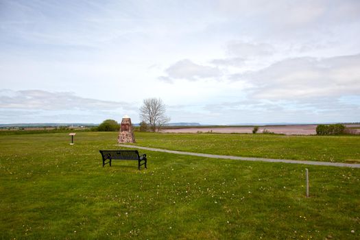 A stone monument marks the settlement spot and deportation area of many Acadian settlers in the 1700s, with Cape Blomidon in background 