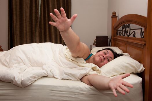 A woman with arms wide open lays in her comfy bed under the covers