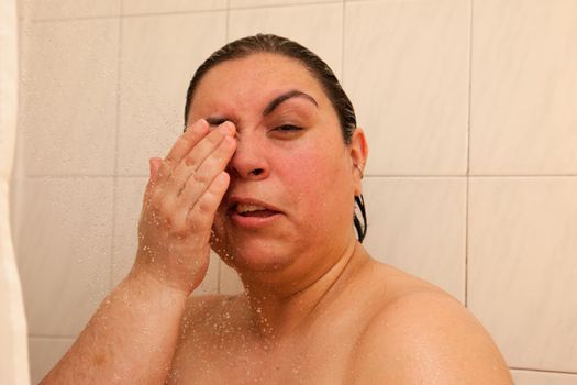 A woman makes a pained expression because she has water in her eye 