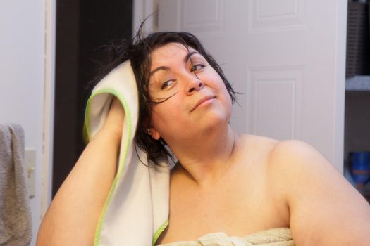 Woman smiles and rubs her short wet dark hair with a towel