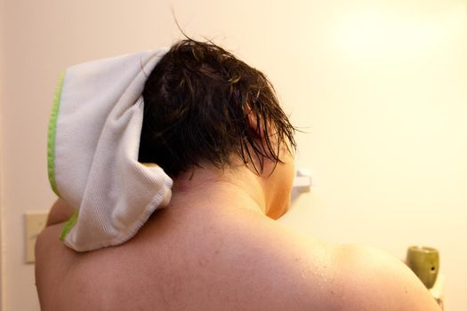 Back of a woman's dark head of hair as she rubs it dry with a towel