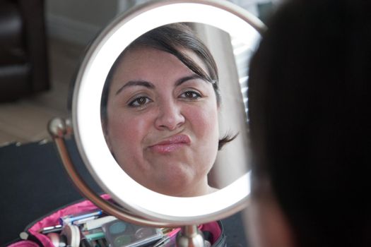 Woman makes a wrinkly unhappy face with her reflection in the mirror 