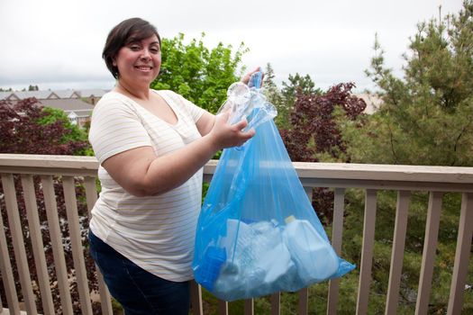 Girl shows off her blue bag of sorted plastics and papers outside 