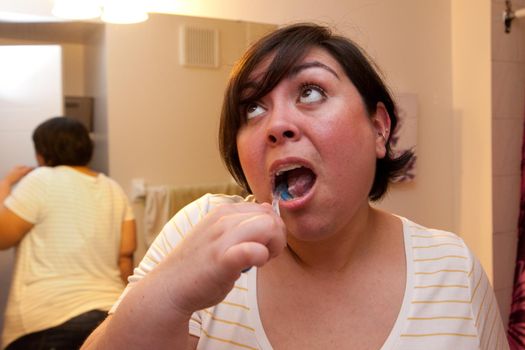 A woman in her bathroom does a good job with an open mouth and teeth brushing 