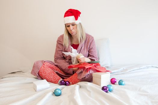 pouting woman in santa hat with christmas ornaments looks at holiday trinkets